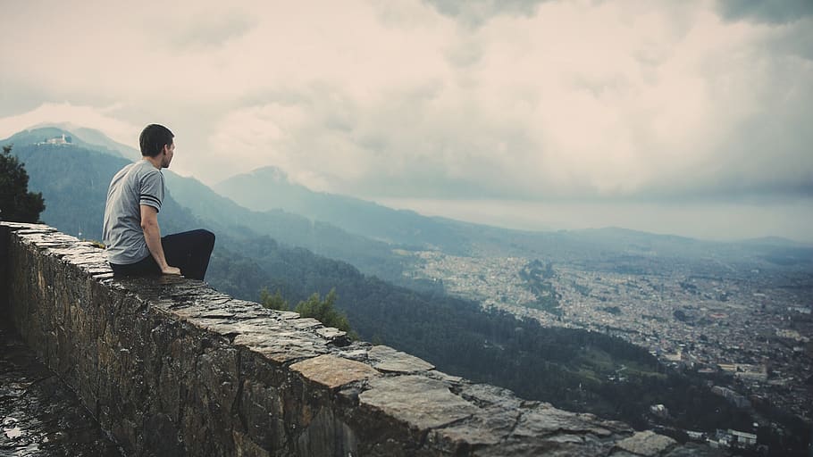 guy, looking, sitting, ledge, city, town, mountains, valleys, hills, clouds