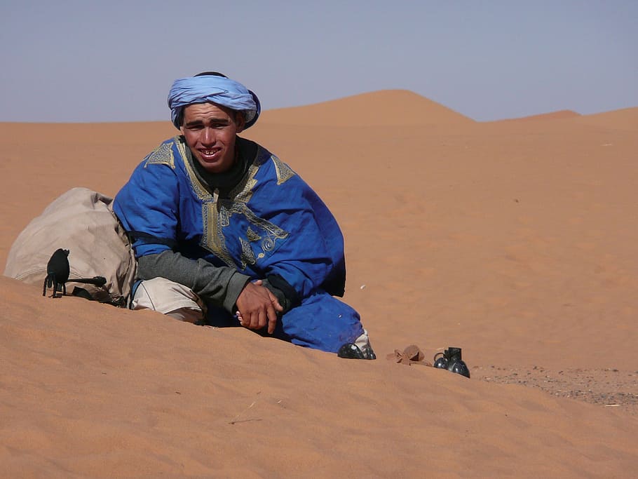man, blue, suit, sitting, brown, sand, daytime, desert, morocco, bedouin