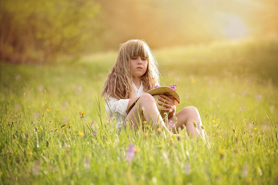 blonde, girl, holding, sun hat, flowers, sitting, green, grass field, day, person