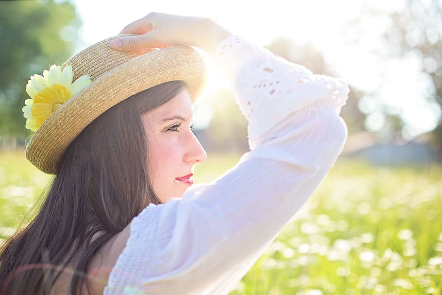 woman, wearing, white, long-sleeved, blouse, holding, brown, hat, yellow, flower