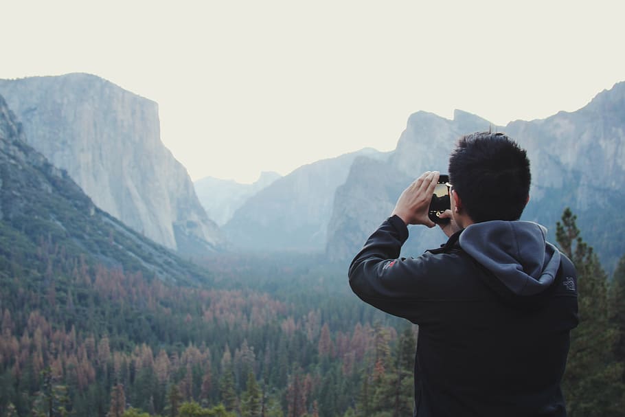 hombre con cámara, hombre, negro, sudadera con capucha, tomando, selfie, montaña, valle, árboles, planta