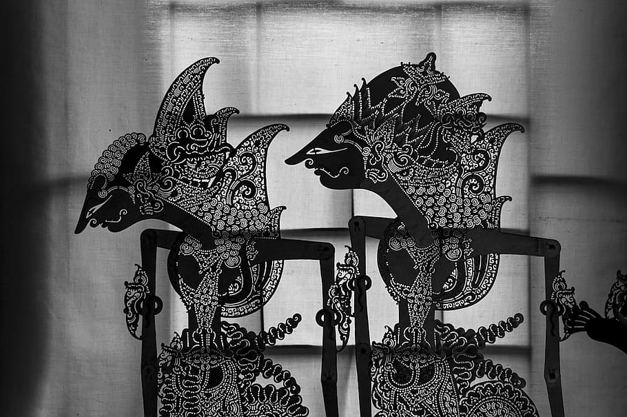  Black and white shadow puppets of two characters from the Ramayana, a Hindu epic, with ornate headpieces and patterns representing goodness and wisdom.