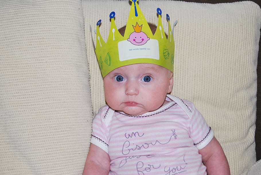 baby, wearing, white, pink, stripe onesie, green, crown, sitting, sofa, stripe