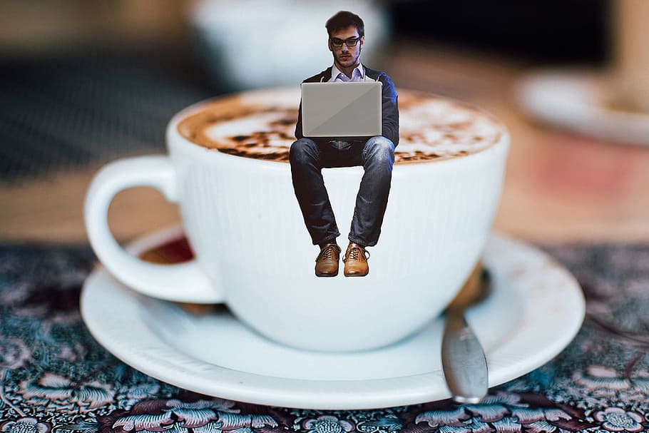 Hombre, azul, chaqueta, usando, computadora portátil, blanco, taza de té, platillo, café, escritor