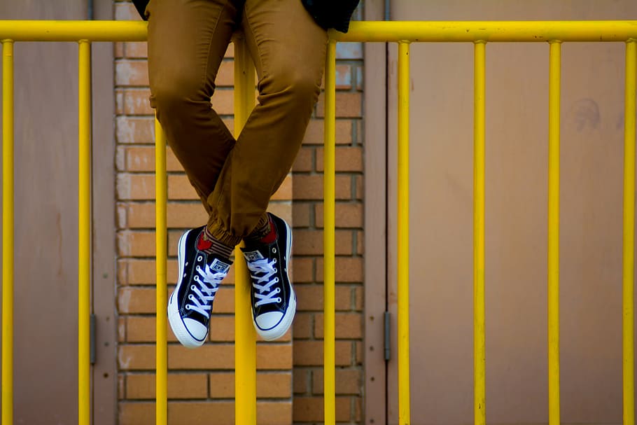 person, sitting, yellow, fence, man, wearing, black, converse, star, low