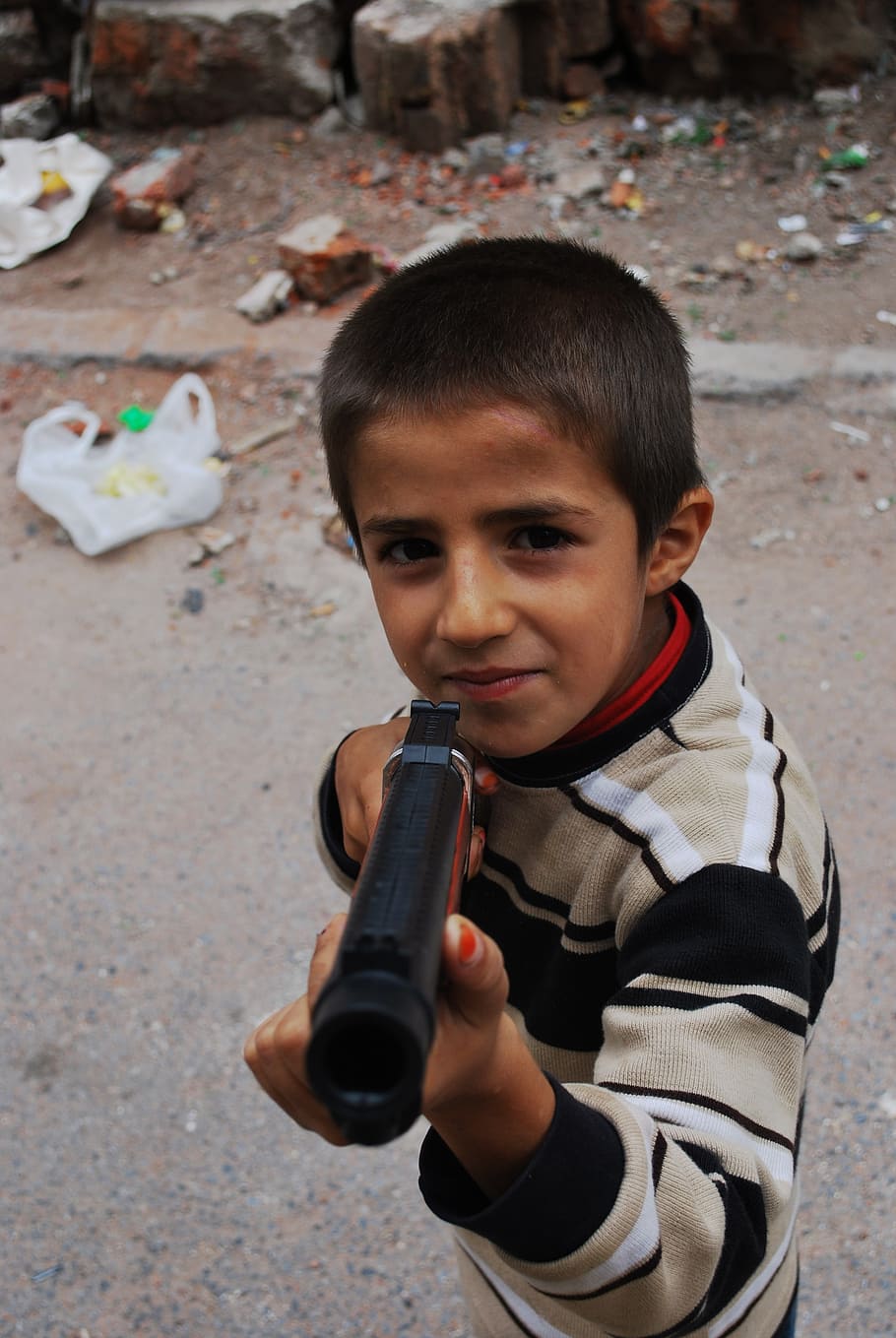 boy, holding, pistol toy, gun, pointing, smiling, trash, child, kid, male