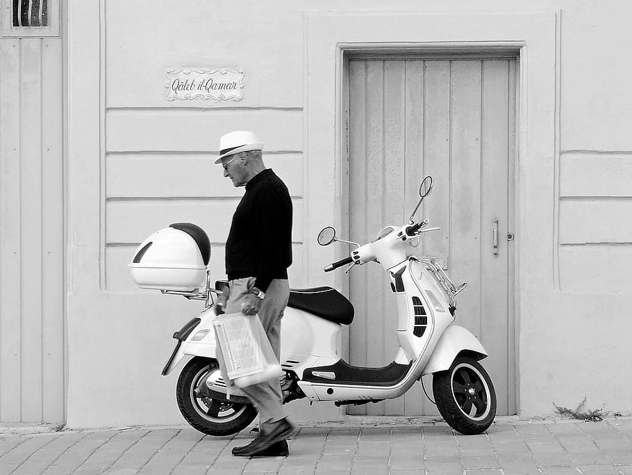 grayscale photography, man, standing, motor scooter, vespa, scooter, walking, motorcycle, transport, urban