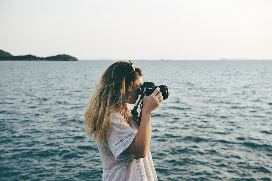 woman, wearing, white, shirt, holding, camera, taking, ocean, daytime, beach