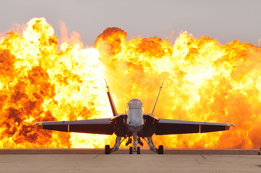 gray fighter aircraft, air show pyrotechnics, military jet, f-18, hornet, blue angel, flightline, detonation, dramatic effect, plane