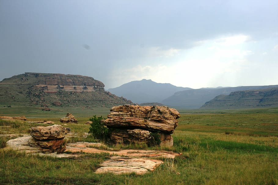 large rock, plate rocks, earthy colors, eminent storm, faroff mountains, green grass, green veld, sky, clouds, landscape