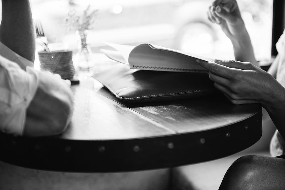 person reading book, people, restaurant, table, menu, order, black and white, cafe, human body part, indoors