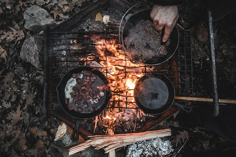 man cooking, grill, using, cooking pad, skillet, daytime, person, cooking, firewood, camp
