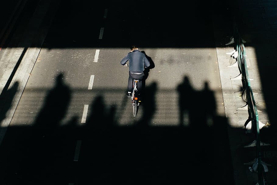 person, riding, bicycle, concrete, road, daytime, dark, street, shadow, people