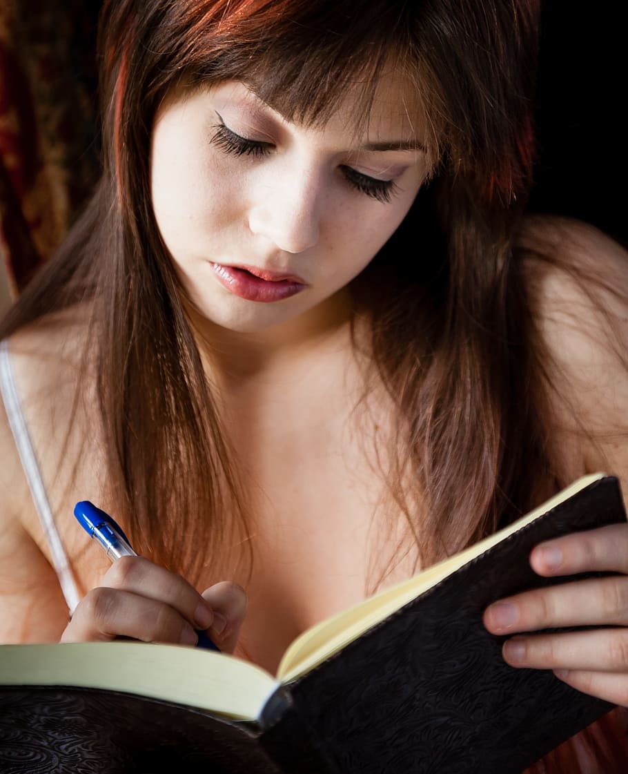 woman, holding, blue, ballpoint pen, black, book, writing, diary, female, sitting