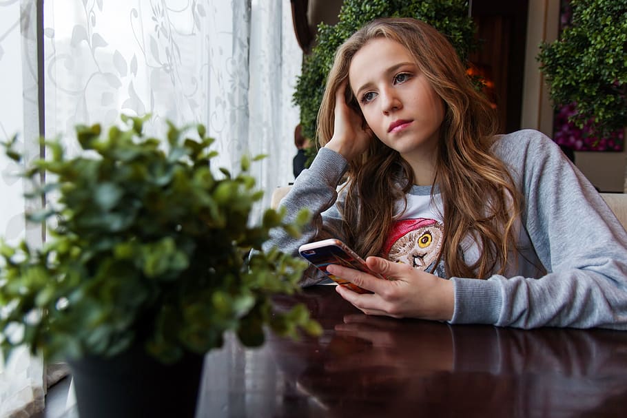 woman, wearing, gray, jacket, girl, teen, café, near the window, window, smartphone