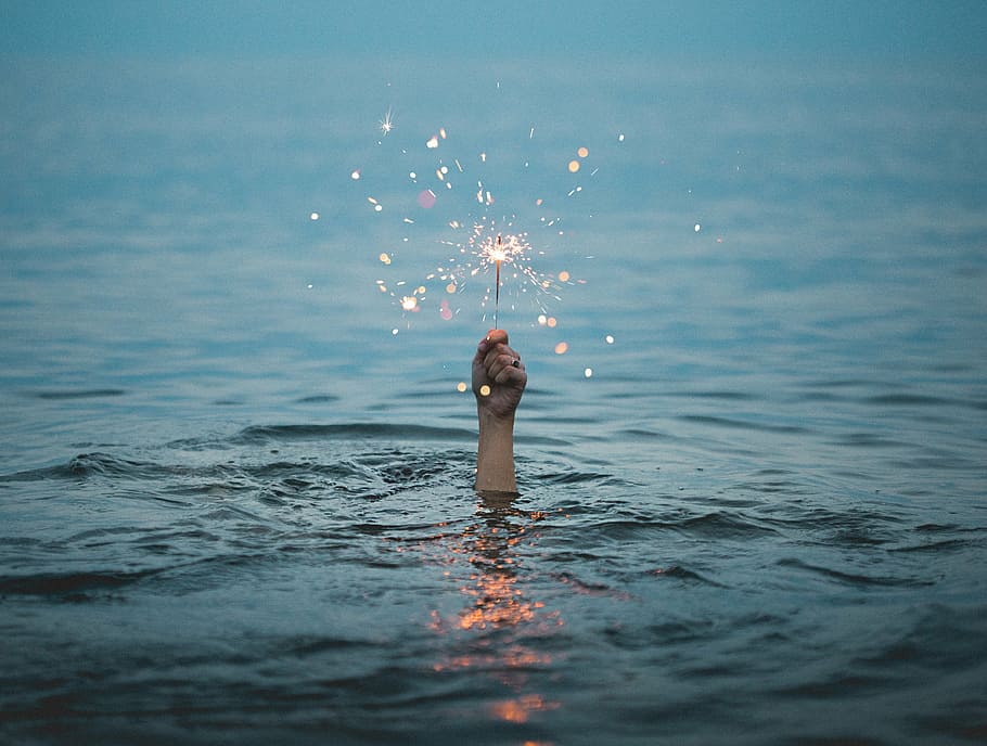 person, holding, sparkler, sea, daytime, selective, focus, photography, human, hand