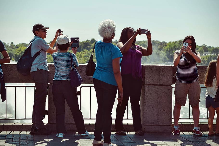 people, holding, smartphones, camera, bridge, taking, daytime, men, women, wall