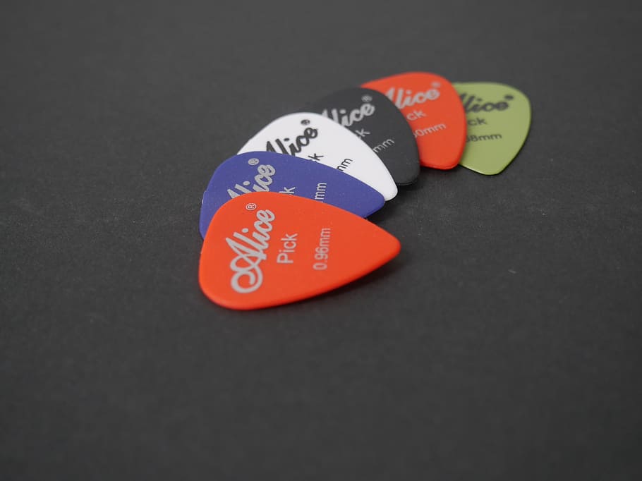 music accessories, music, guitar pick, close-up, indoors, red, text, studio shot, communication, western script