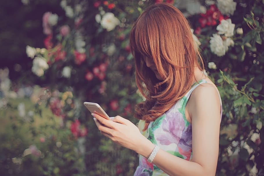 mujer, vistiendo, floral, sin mangas, superior, sosteniendo, oro iphone 6, oro, iPhone 6, al aire libre