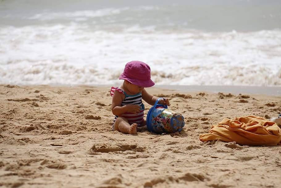 Bebé, vistiendo, púrpura, sombrero, jugando, arena, océano, durante el día, niño jugando, playa