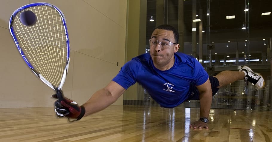 man, holding, purple, white, racquetball racket, brown, wooden, floor, racquetball, player