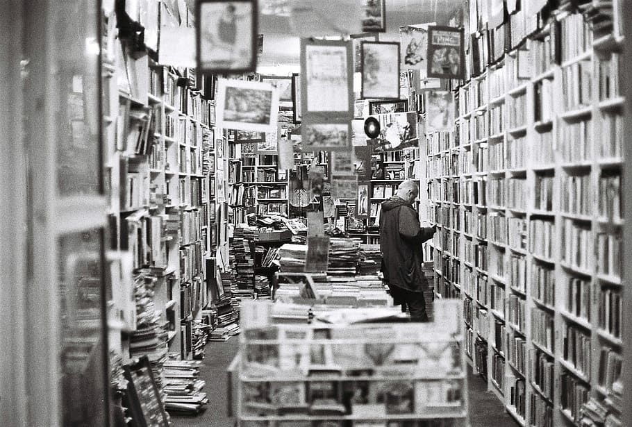 grayscale photo, man, front, wooden, shelf, bookstore, books, old bookstore, vintage, bookshelf
