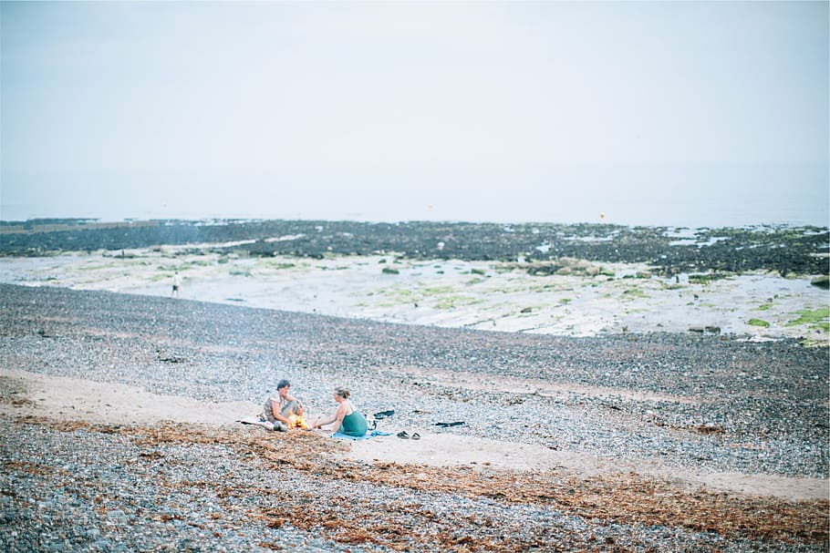 man, woman, sitting, beach, three, person, sand, daytime, shore, waves