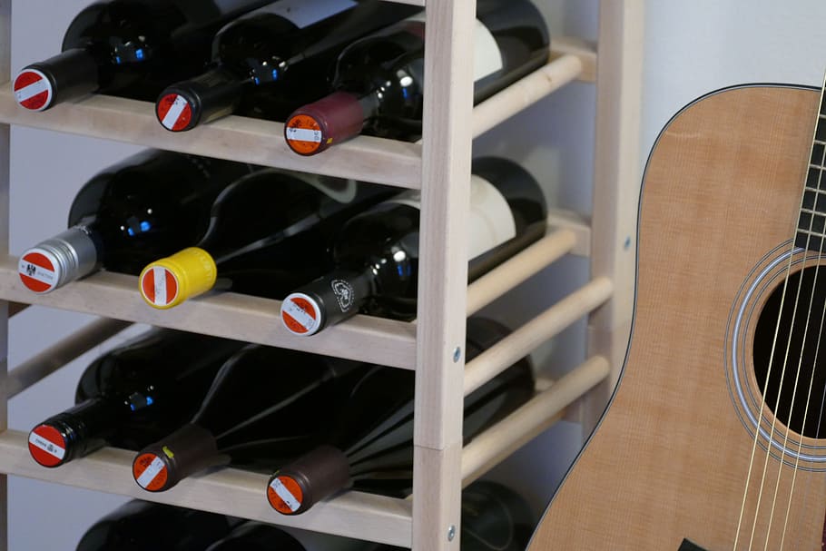 guitar, wine, wine rack, alcohol, wine bottle, indoors, shelf, in a row, drink, large group of objects