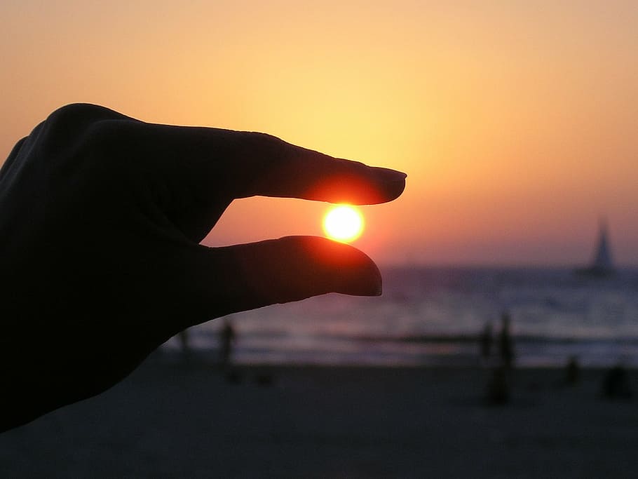 silhouette photo, sunset, person, hand, sun in the hand, fingers, silhouette, sky, seashore, ocean
