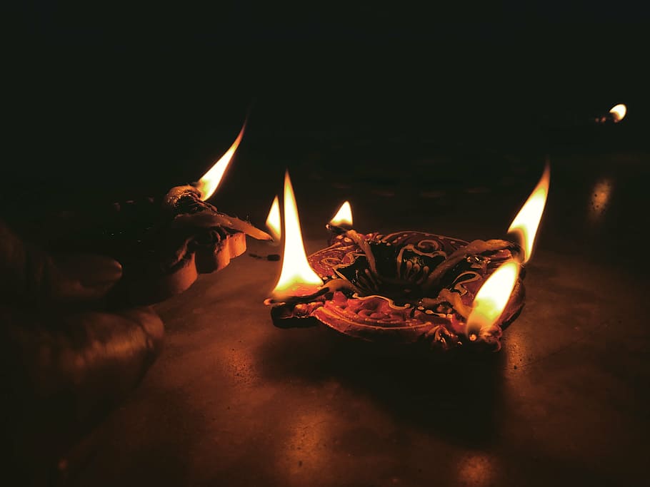 person lighting candles, candle, light, fire, flame, dark, night, ashtray, table, burning