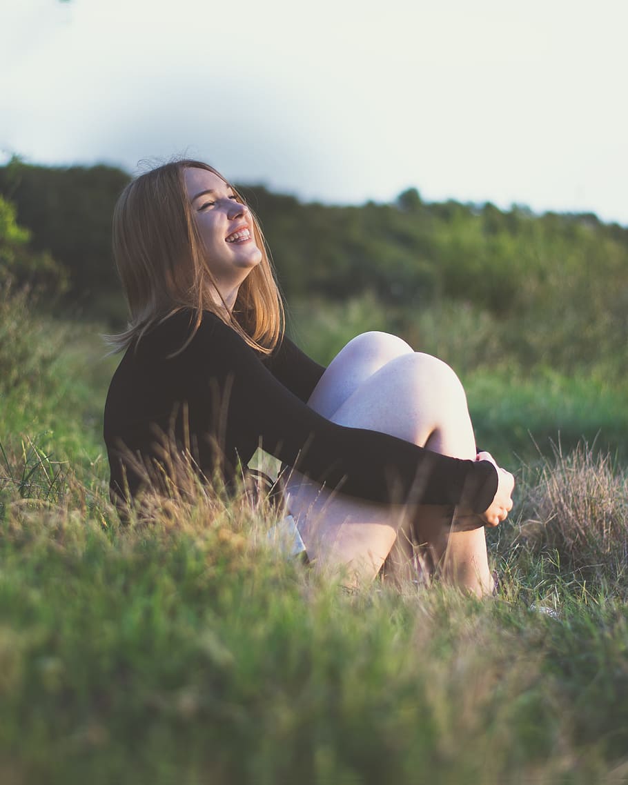 woman, smiling, white, sitting, grass field, girl, sunset, sun, light, yellow