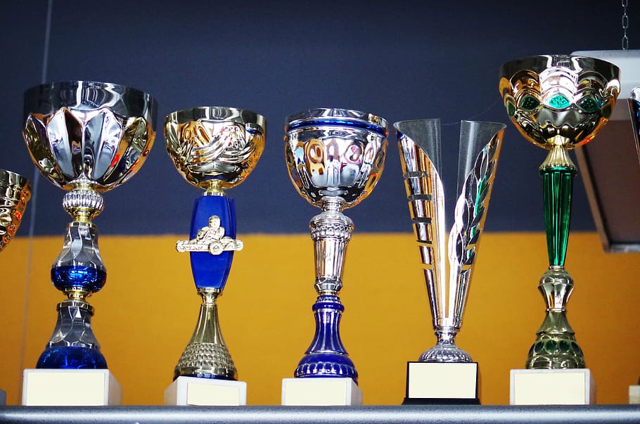 cinco trofeos de colores variados, copas, ganador, recompensa, trofeo, premio, éxito, logro, sin gente, brillante