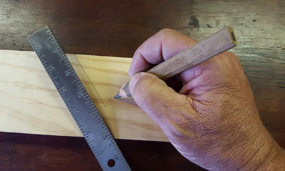 person, holding, brown, wooden, pencil, stainless, steel ruler, measuring, slab, stainless steel