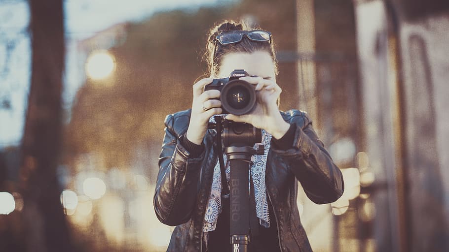 woman, holding, camera, taking, adult, black leather jacket, blur, canon, capture, city