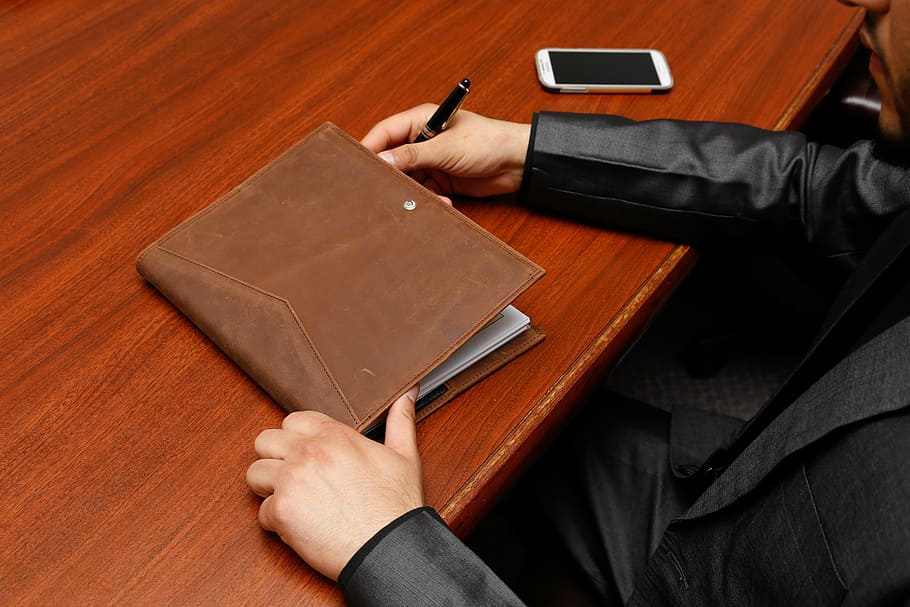 person, sitting, brown, wooden, table, organizer, brown leather, executive, note, male