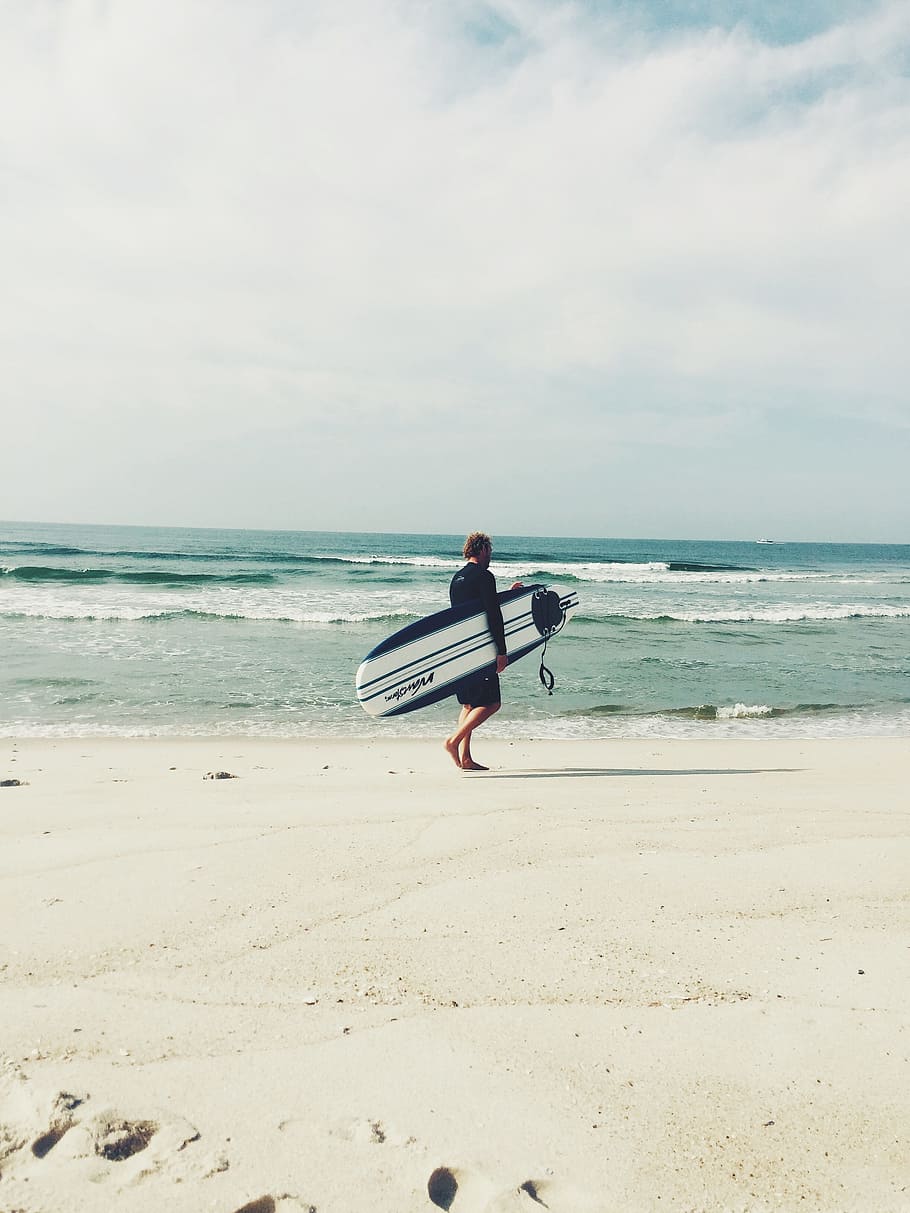Hombre, transporte, blanco, azul, tabla de surf, caminar, orilla del mar, foto, negro, durante el día