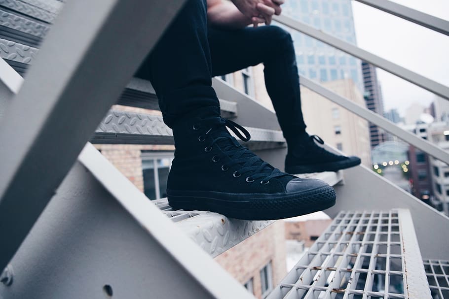 person, wearing, black, converse, sneakers, sitting, metal staircase, daytime, guy, man