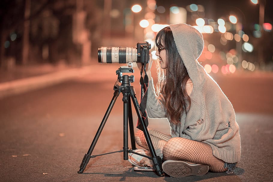 woman, grey, hooded jacket, sits, road, using, dslr camera, tripod, night, camera