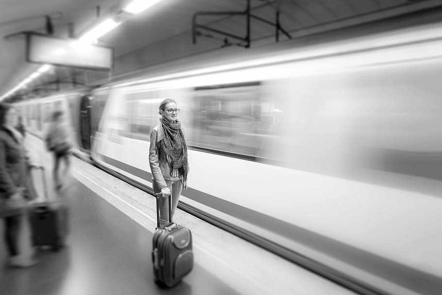 grayscale photo, woman, holding, trolley bag, gray, scale, portrait, standing, behind, train