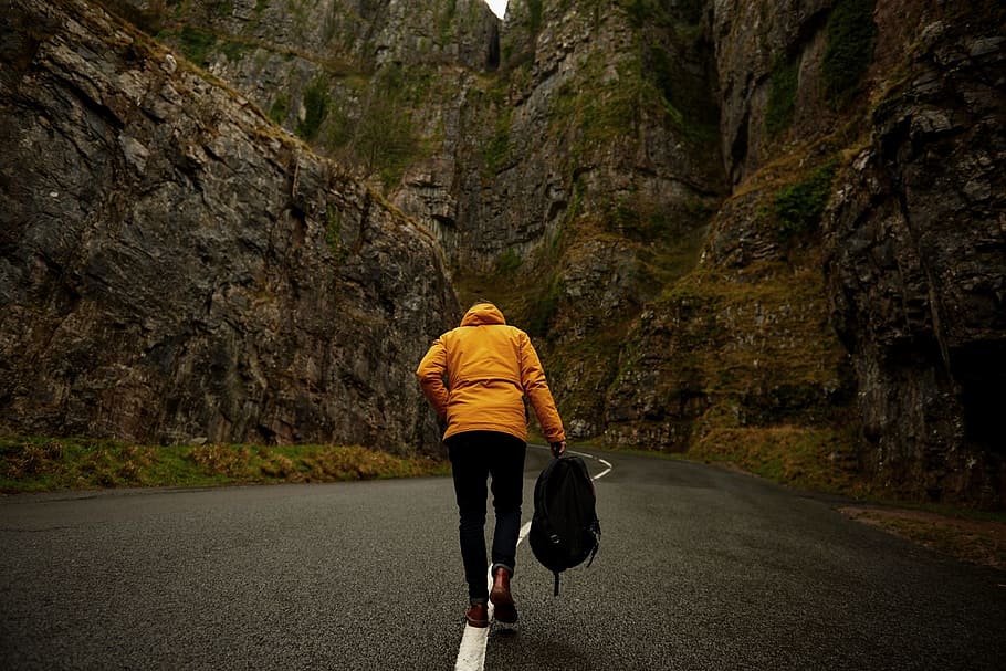 person, wearing, yellow, hoodie, black, pants, holding, backpack, walking, roadway