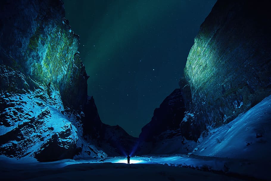 person between mountains, ice, cave, rocks, snow, winter, flashlights, people, travel, outdoor