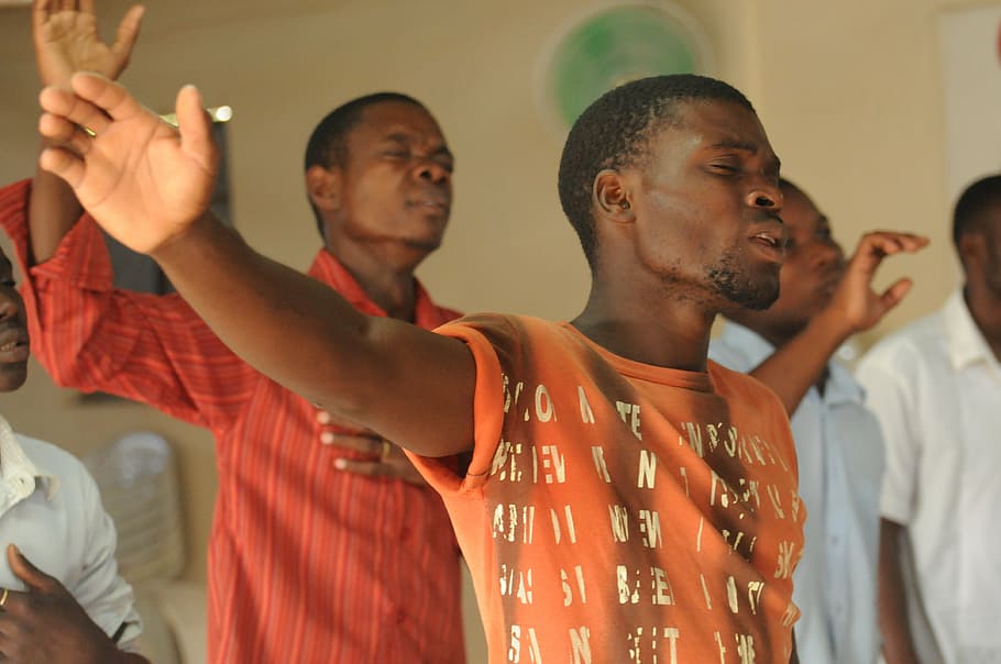 man, wearing, orange, crew-neck shirt, raising, right hand, worship, praise, singer, black