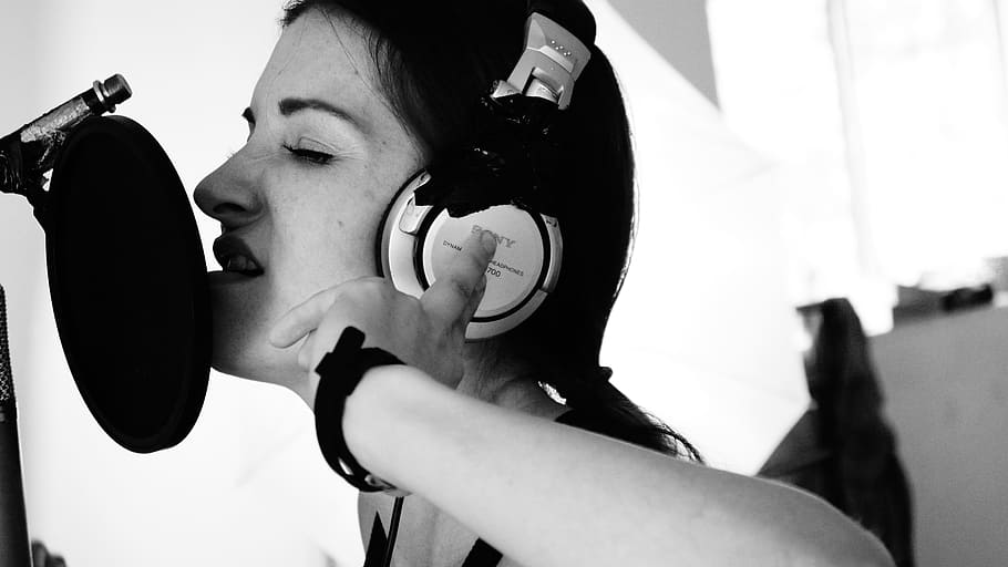 greyscale photo, woman, wearing, over-ear headphones, pop filter, grayscale, condenser microphone, headphones, singer, musician
