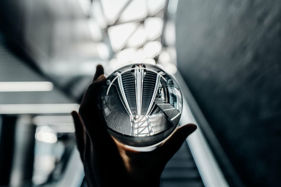 person, holding, clear, glass sphere, glass, escalator, bokeh, hand, blur, round