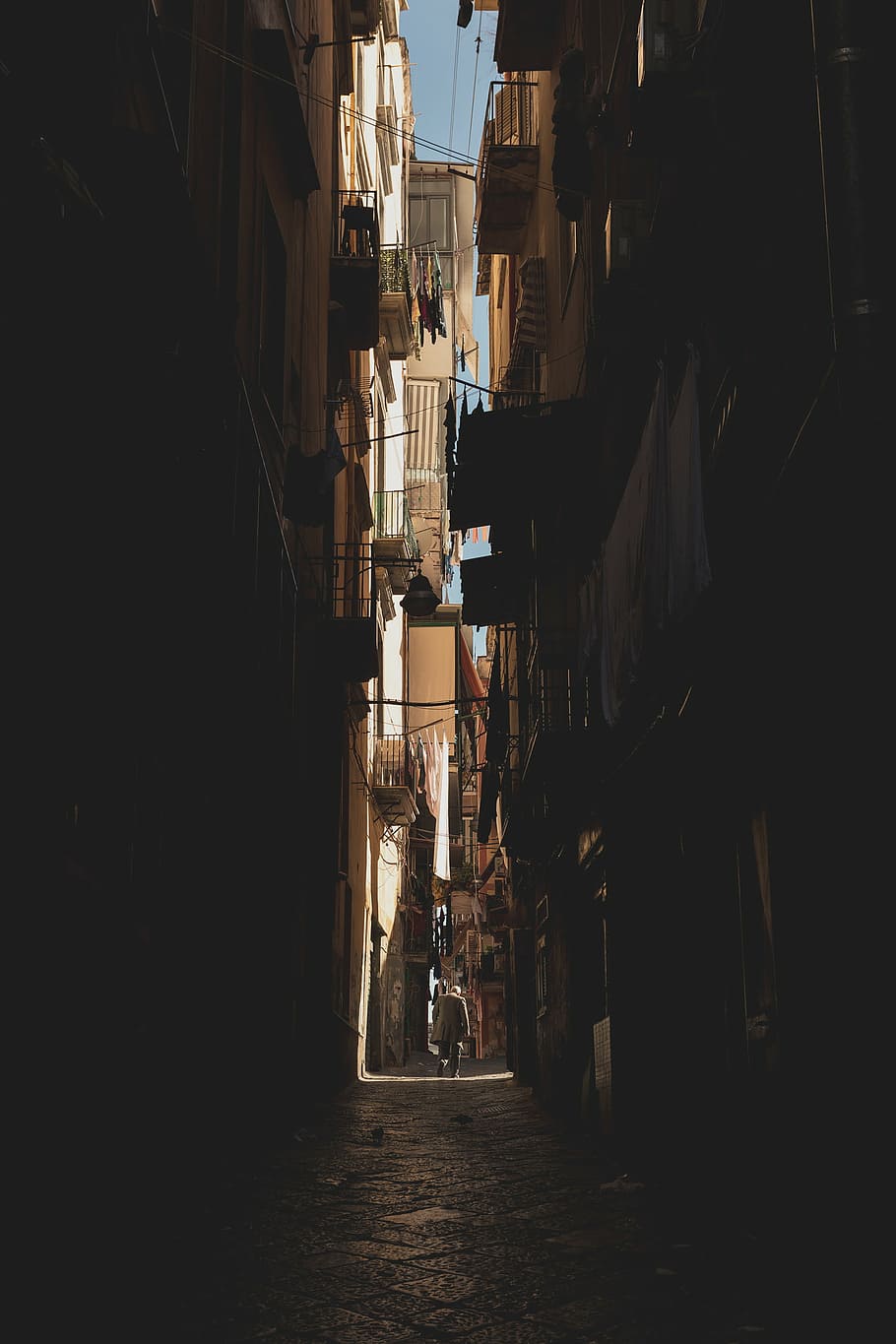 person, walking, pathway, concrete, buildings, daytime, architecture, building, dark, alley