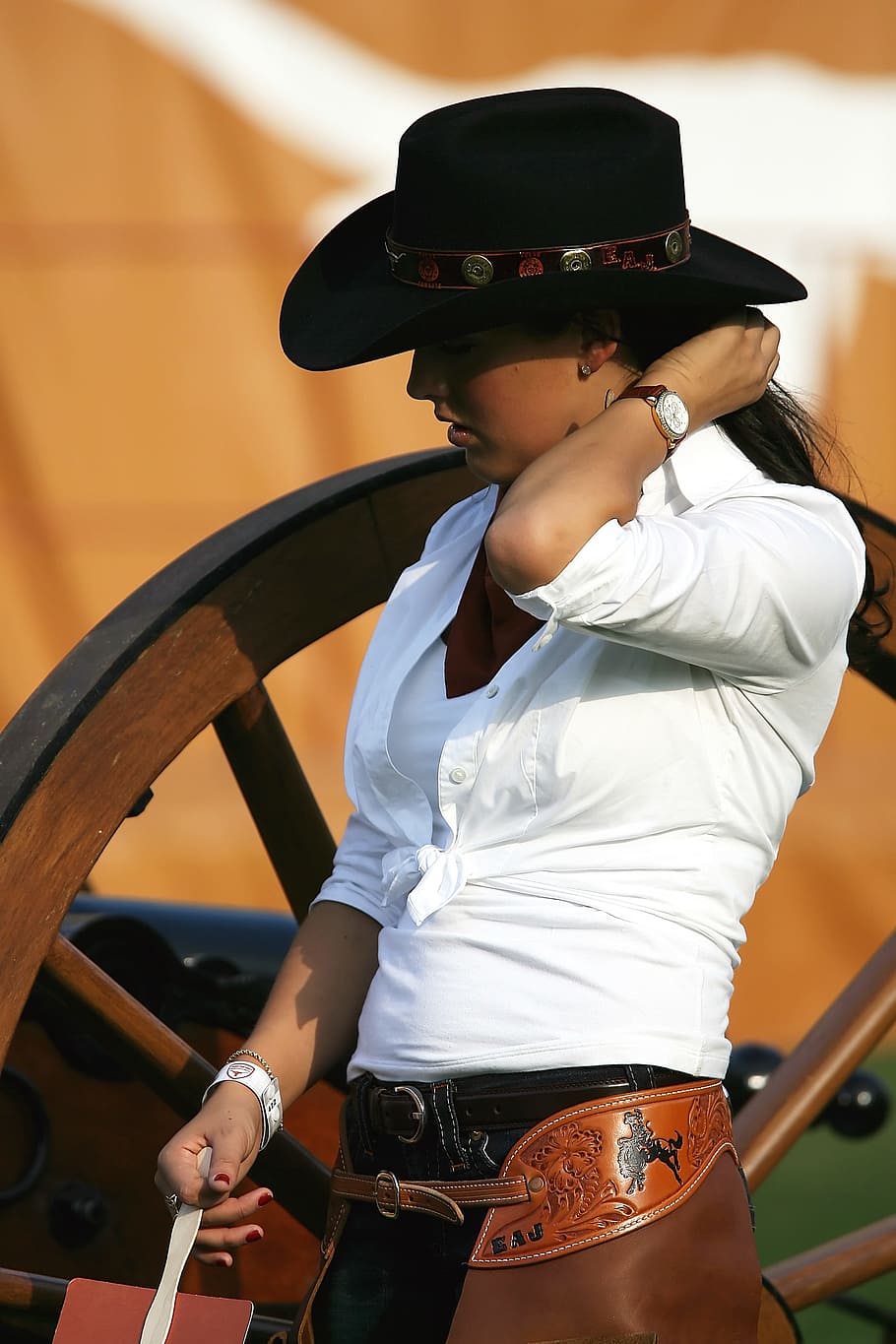 woman, white, collared, button-up, long-sleeved, dress shirt, black, cowboy hat, standing, brown