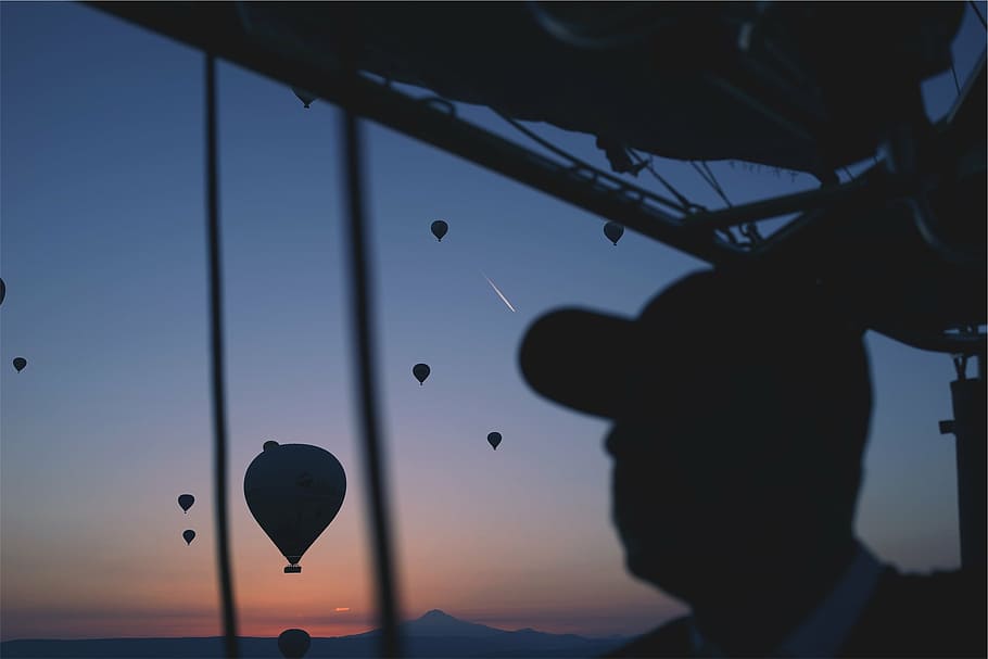 silhouette photography, man, sitting, inside, air balloon, wearing, black, ball, cap, near