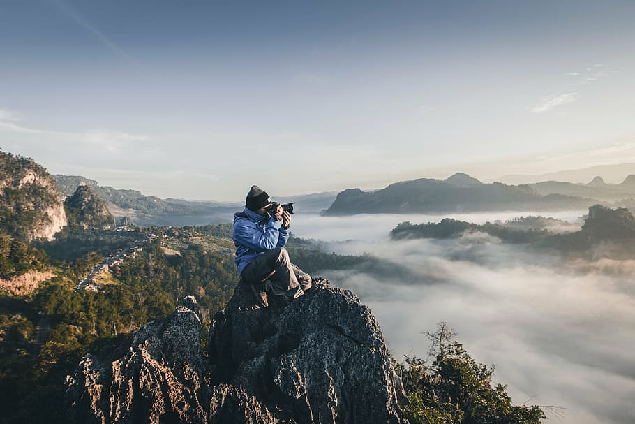 man, sitting, gray, rocky, mountain, capturing, aerial, body, water, surrounded