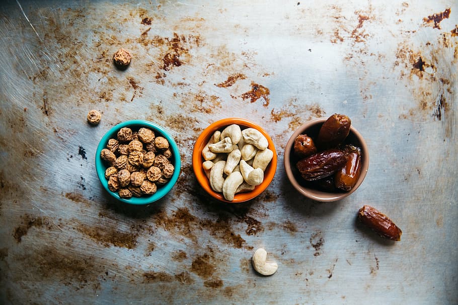 assorted nuts, cashew, nuts, peanuts, prunes, bowl, raisins, table, dirt, food