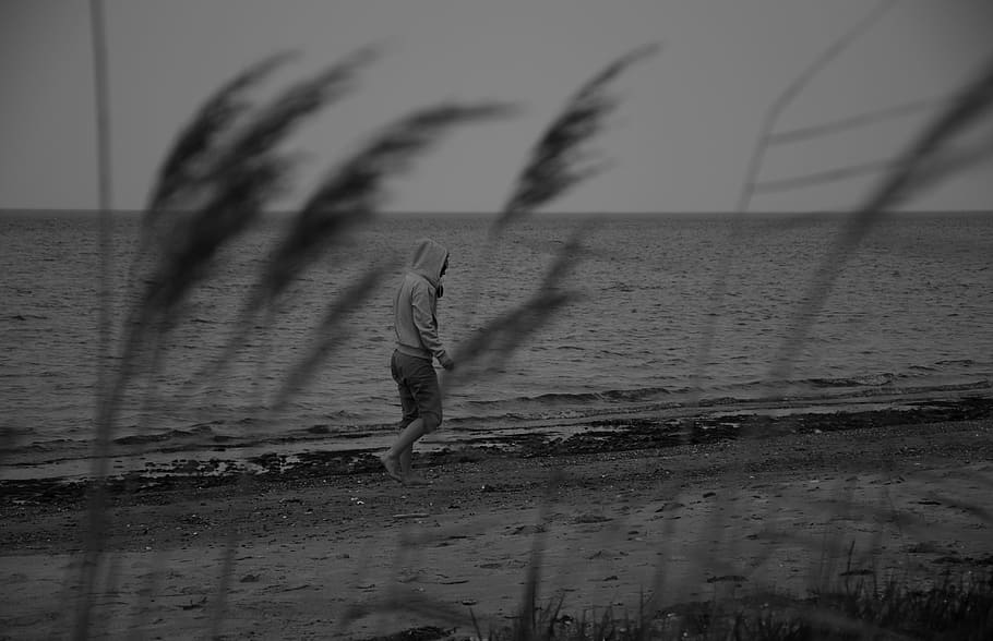 foto skala abu-abu, orang, hoodie, berjalan, pantai, melankolis, depresi, keputusasaan, kesedihan, kesenangan
